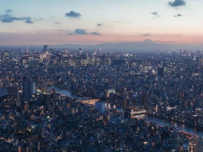 Panoramisch uitzicht op de skyline van Tokio bij zonsondergang, met verlichte wolkenkrabbers en een rivier.
