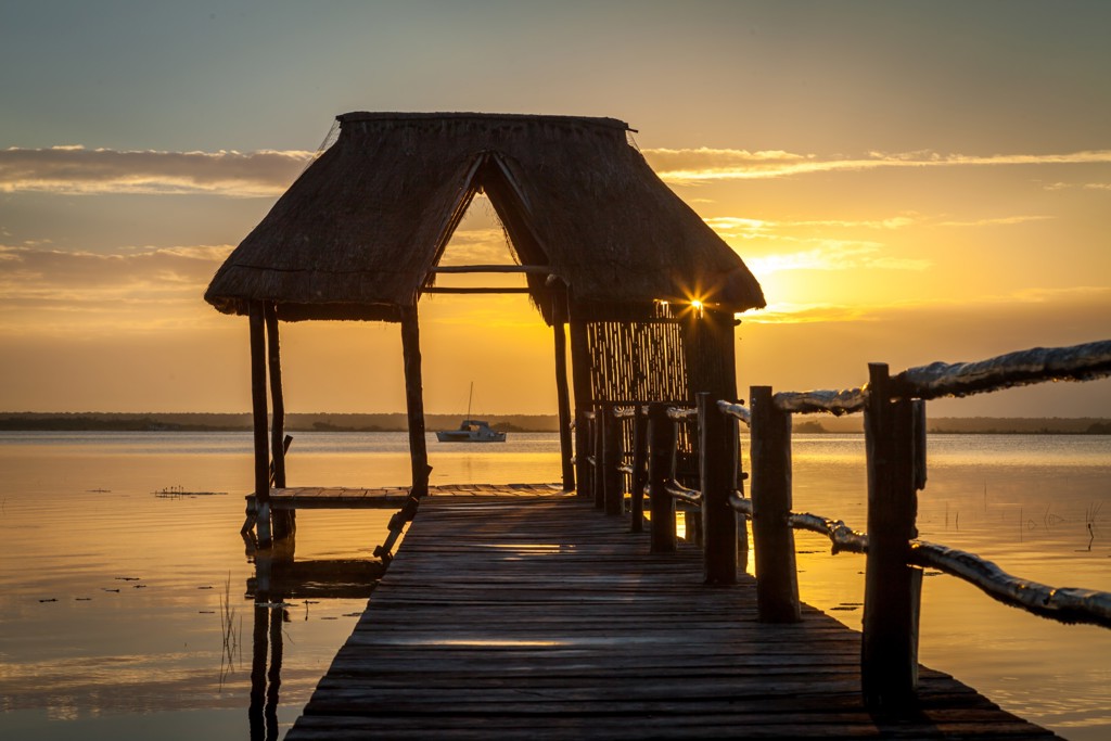 Houten steiger met rieten hut bij zonsondergang aan een lagune in Mexico, tijdens een groepsrondreis.