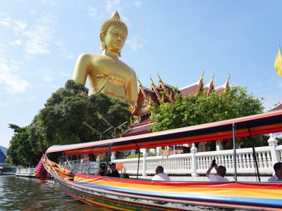 Boottocht langs een tempel met groot gouden Boeddhabeeld in Thailand.