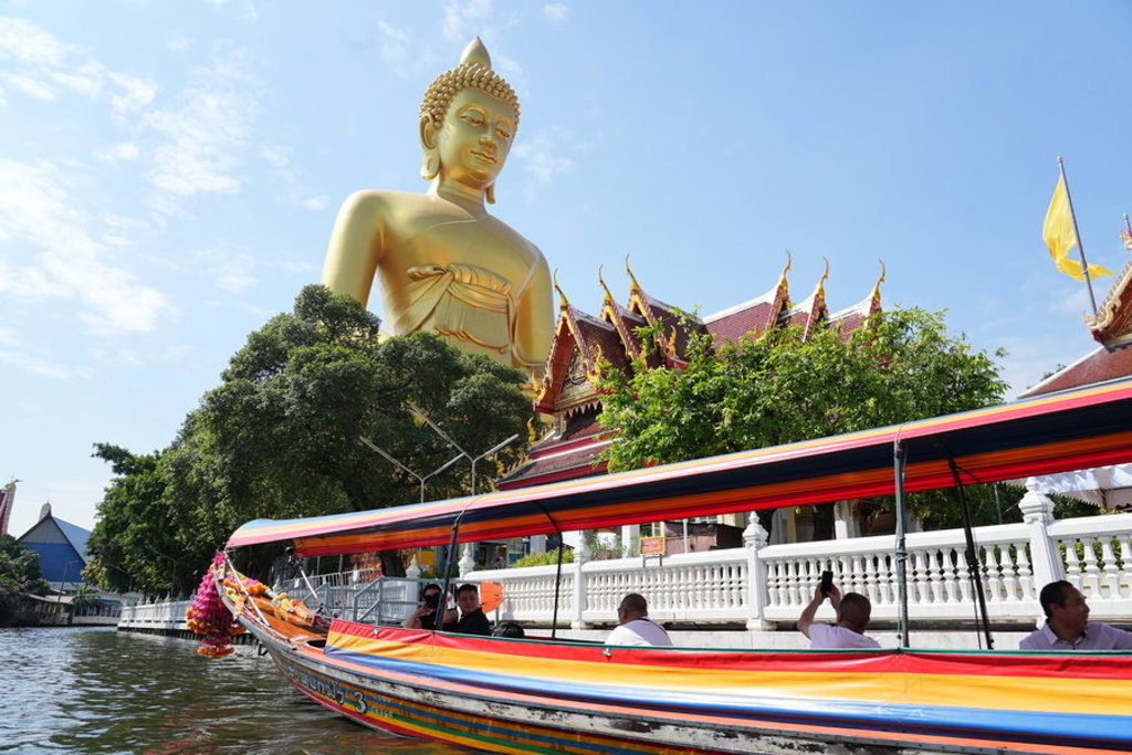 Boottocht langs een tempel met groot gouden Boeddhabeeld in Thailand.