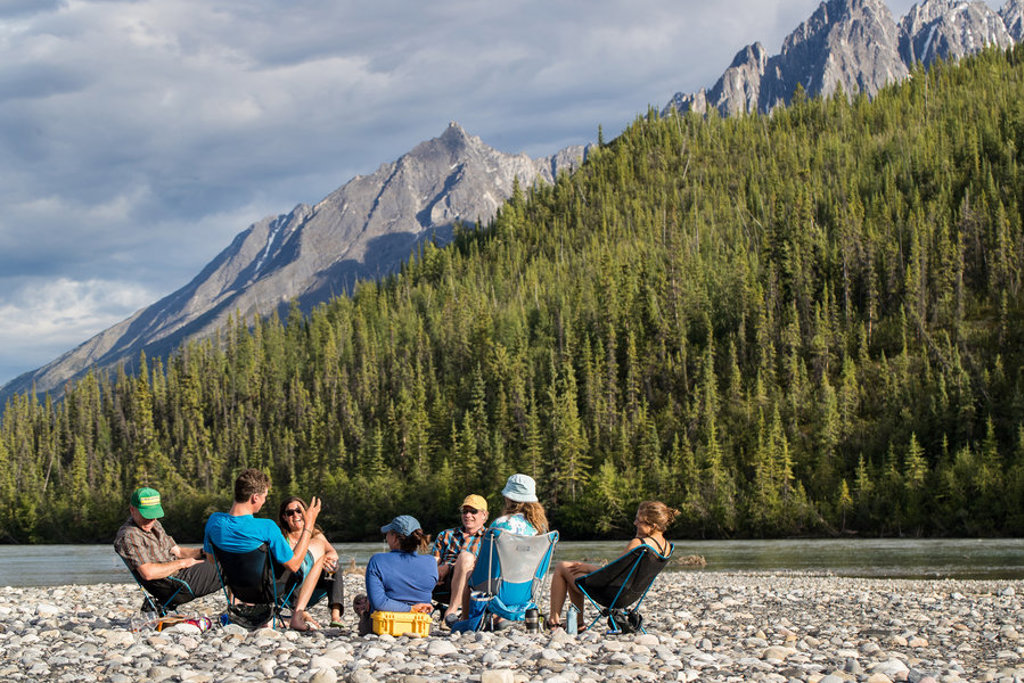 Familie ontspant aan een rivier met uitzicht op de Rocky Mountains tijdens familiereis Canada West.