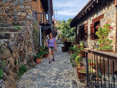 Wandelaar in een smalle, geplaveide steeg tussen stenen huizen in een traditioneel dorp op Cyprus.