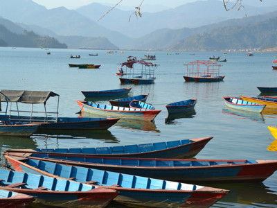 Roeiboten op het Phewa-meer in Pokhara met uitzicht op de bergen, Nepal.