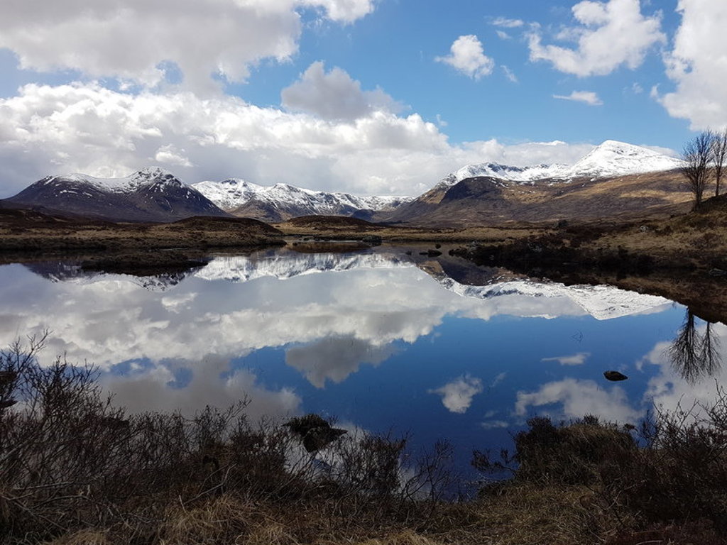 Sneeuwtoppen en wolken weerspiegeld in een loch in de Schotse Hooglanden tijdens een groepsrondreis Schotland.