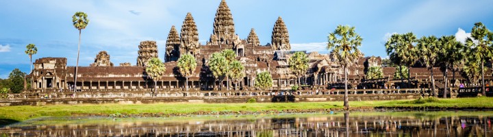 Angkor Wat tempelcomplex in Cambodja met weerspiegeling in de vijver en palmbomen op de voorgrond.