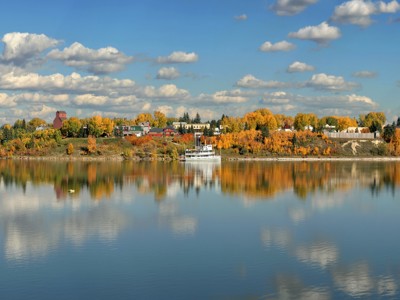 Herfstkleuren langs een rivier in Canada met een boot en weerspiegeling van wolken in het water.