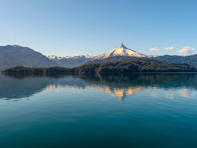 Azuurblauw meer met weerspiegeling van besneeuwde bergtoppen in Patagonië.