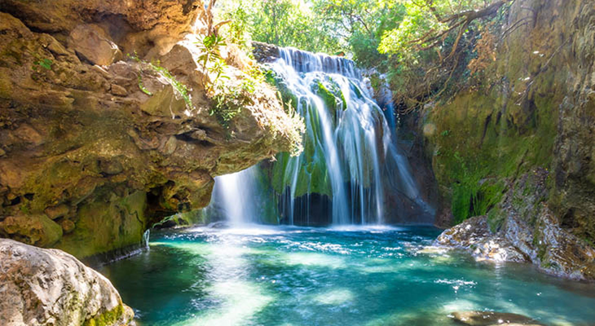 Waterval met helderblauw water in een groene kloof in Marokko.