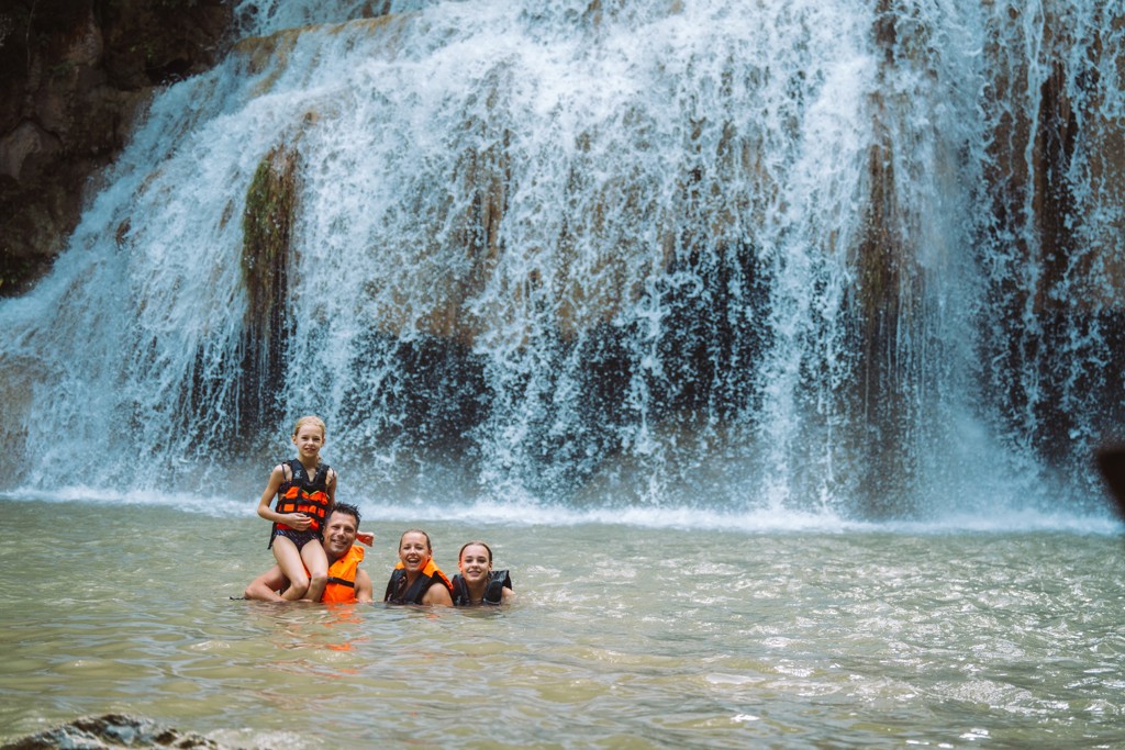 Gezin zwemt bij een waterval in Thailand tijdens de Familiereis Thailand Chill & Adventure.