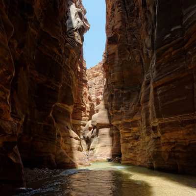 Smalle kloof met hoge rotswanden en stromend water in Wadi Mujib, Jordanië.