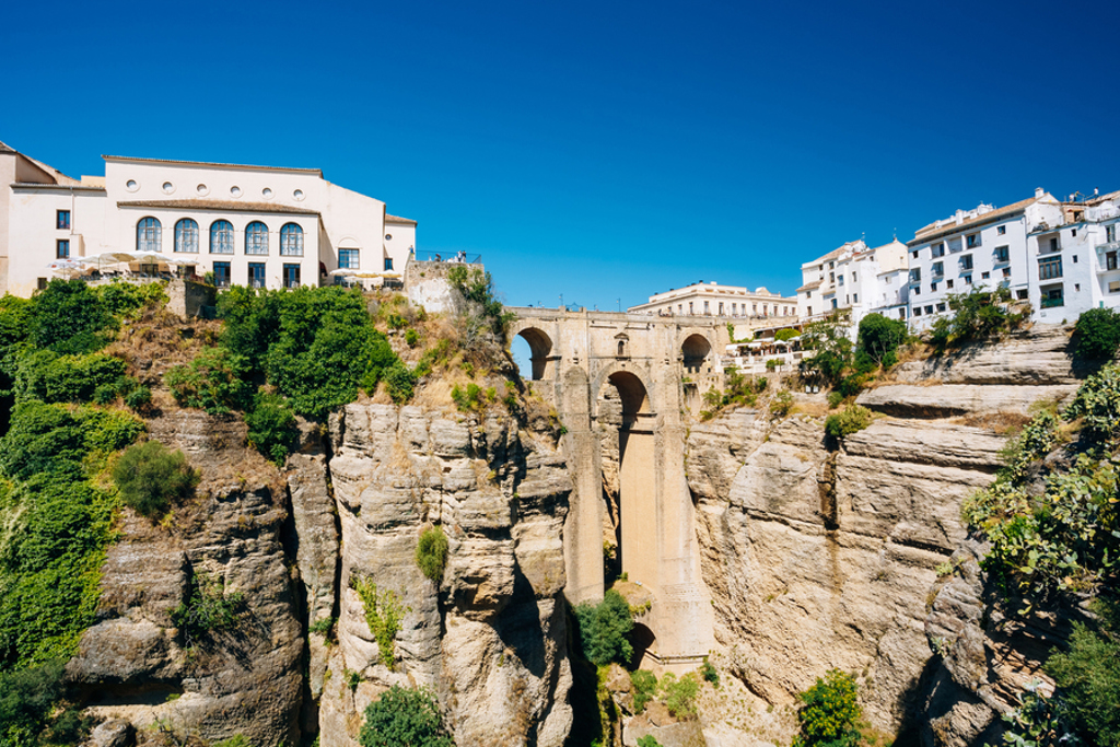 Ronda in Andalusië met de Puente Nuevo-brug over de El Tajo-kloof onder een heldere blauwe lucht.
