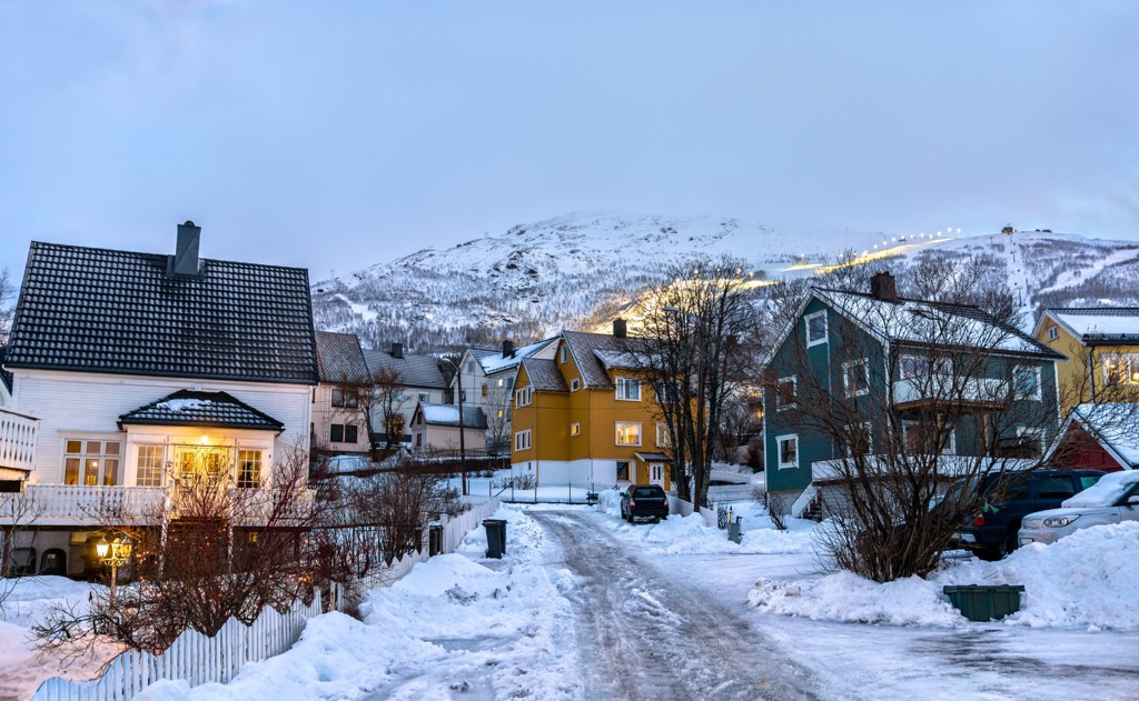 Sneeuwbedekt dorp met kleurrijke houten huizen in Zweeds en Noors Lapland tijdens de winter.
