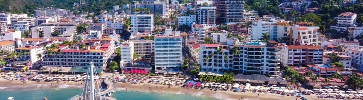 Uitzicht op de kust en skyline van Puerto Vallarta met strand, pier en boten in de baai.