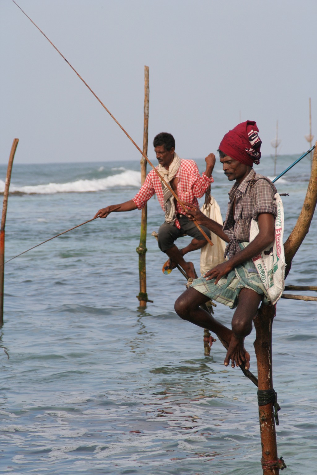 Steltvissers vissen in zee aan de kust van Sri Lanka tijdens een familiereis langs hoogtepunten.