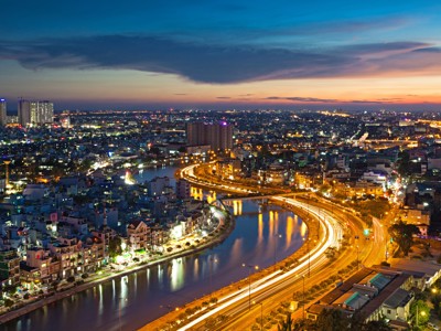 Avondpanorama van Ho Chi Minhstad met rivierbocht en verlichte snelweg, Route Vietnam.