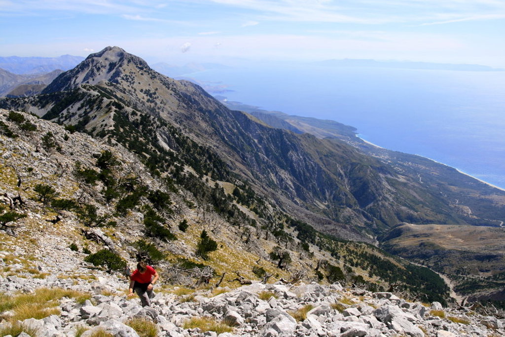 Wandelaar op bergpad met uitzicht op de Albanese Rivièra en de Ionische Zee tijdens een wandelvakantie in Albanië.