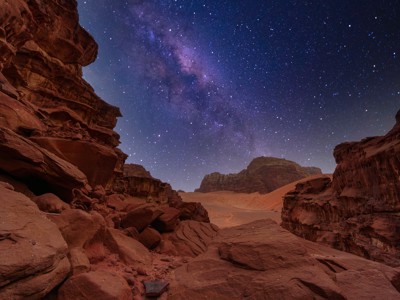 Sterrenhemel boven de rotsen en zandduinen van Wadi Rum in Jordanië.