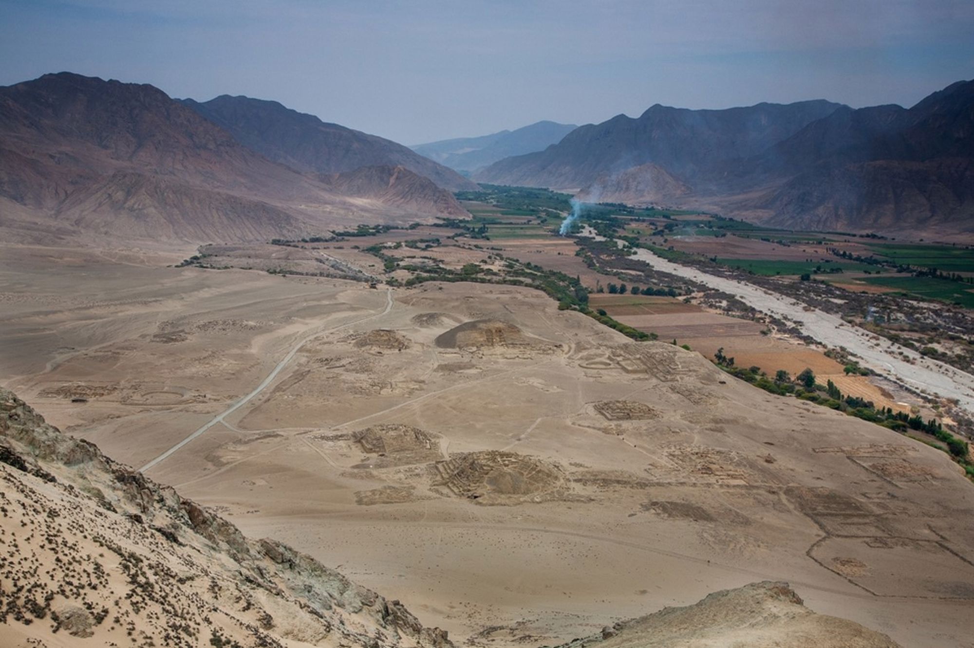 Uitzicht over de Nazca-woestijn met geogliefen en rivierdal tussen de bergen in Peru.