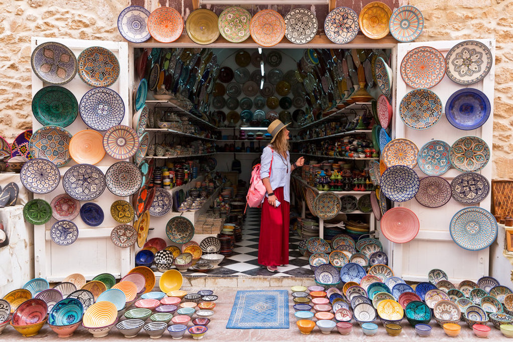 Reiziger in Marokkaanse souk bij winkel vol kleurrijk aardewerk en schalen tijdens groepsrondreis Marokko Kort.