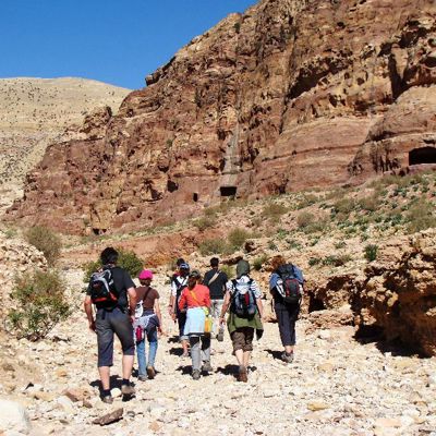 Wandelaars tijdens een familiereis in Jordanië, door een rotsachtige woestijnkloof.