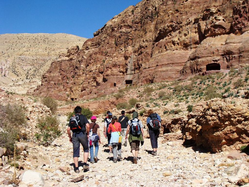 Wandelaars tijdens een familiereis in Jordanië, door een rotsachtige woestijnkloof.