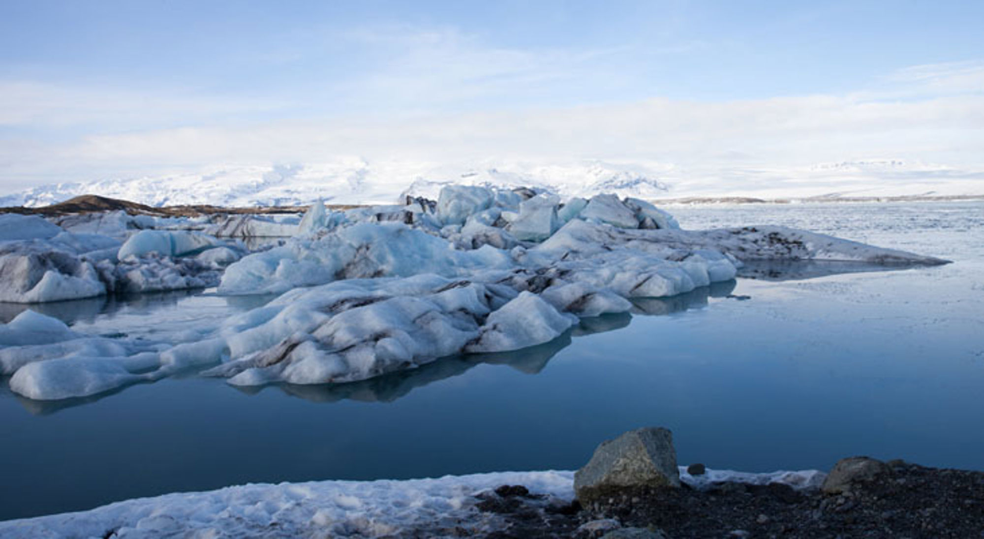 Drijvende ijsbergen in de gletsjerlagune Jökulsárlón in IJsland, met besneeuwde bergen op de achtergrond.