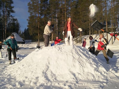 Familie schept sneeuw in Lapland tijdens winterreisroute Finland.