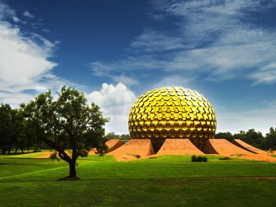 Gouden Matrimandir-tempel in Auroville bij Pondicherry, omringd door groen en onder een blauwe lucht.