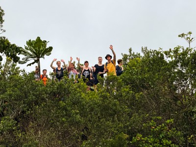 Groepsreizigers wandelen door het groene landschap van Costa Rica en zwaaien naar de camera.