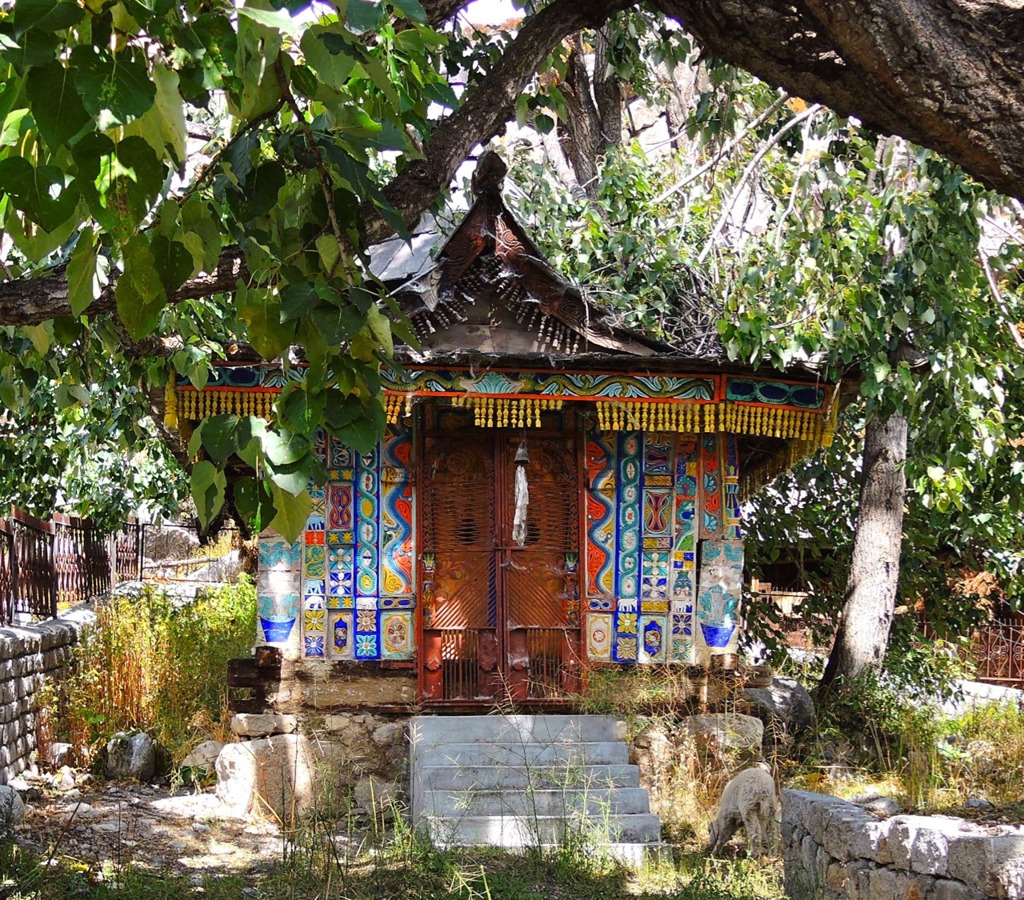 Kleurrijk boeddhistisch tempeltje onder bomen in Ladakh, India.