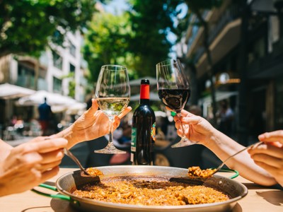 Samen paella eten met een glas witte en rode wijn op een zonnig terras in Andalusië.