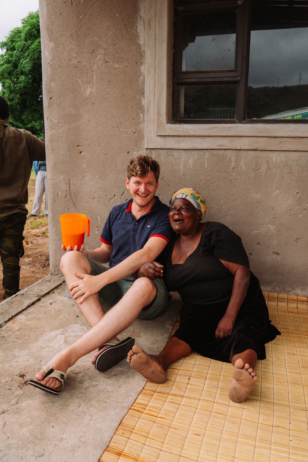 Reiziger lacht met lokale vrouw voor een huis tijdens 22-35ers reis Zuid-Afrika.