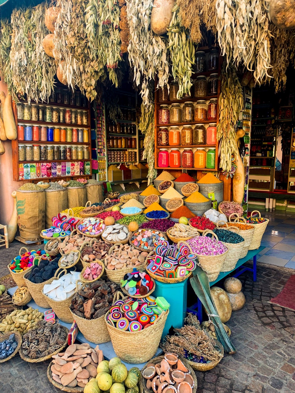 Kleurrijke kruiden- en specerijenmarkt in Marokko met manden vol poeders, kruiden en potten in een winkel.
