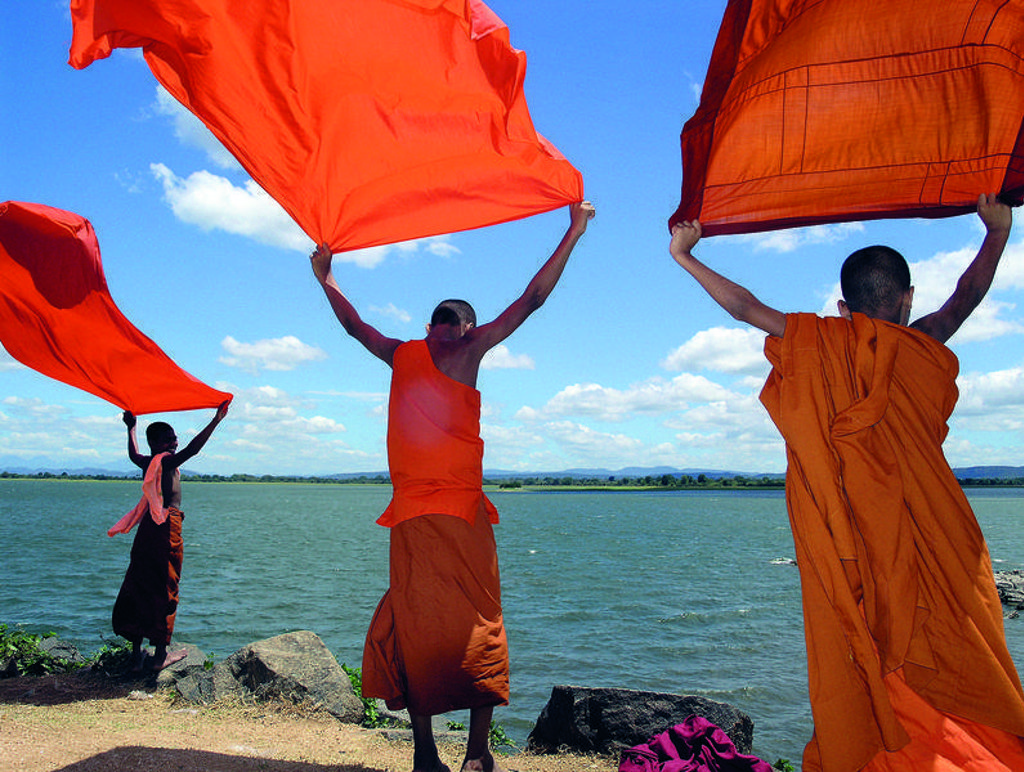 Boeddhistische monniken drogen oranje gewaden aan een meer in Sri Lanka tijdens een familiereis Sri Lanka en Malediven.