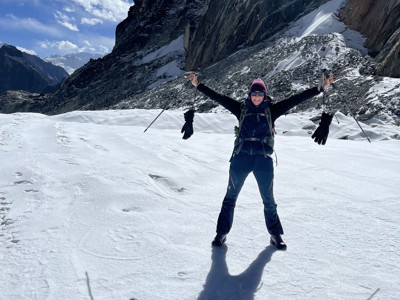 Trekker op besneeuwde bergpas tijdens de Route Nepal Everest Base Camp, met rotswanden en blauwe lucht.