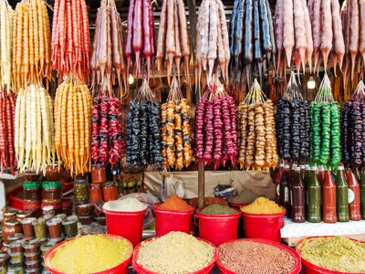 Kleurrijke kraam op een markt in Georgië met hangende churchkhela en bakken met kruiden en specerijen.