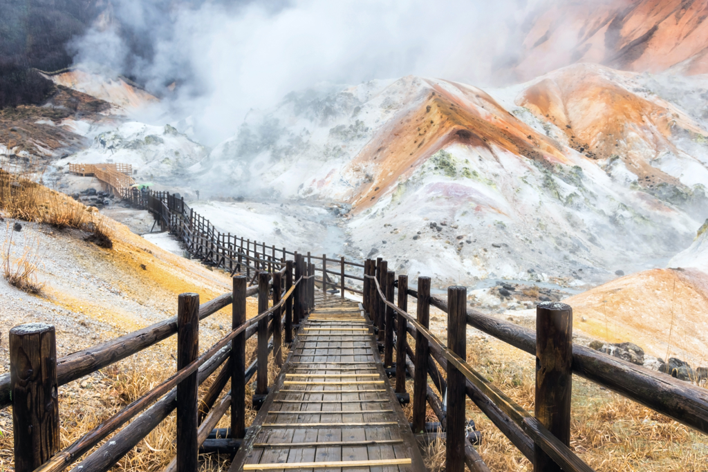 Houten wandelpad door een dampend vulkaanlandschap in Japan tijdens een familiereis.