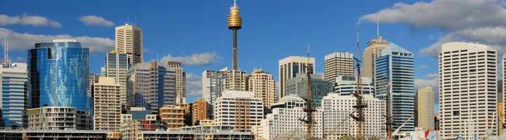 Skyline van Sydney bij Darling Harbour met de Sydney Tower en een historisch zeilschip in de haven.