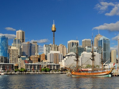 Skyline van Sydney bij Darling Harbour met de Sydney Tower en een historisch zeilschip in de haven.