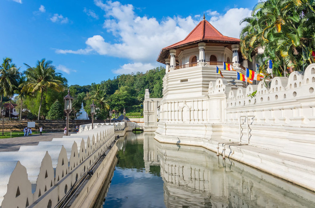 Tempel van de Tand in Kandy, Sri Lanka, met witte muren, vijver en boeddhistische vlaggen.