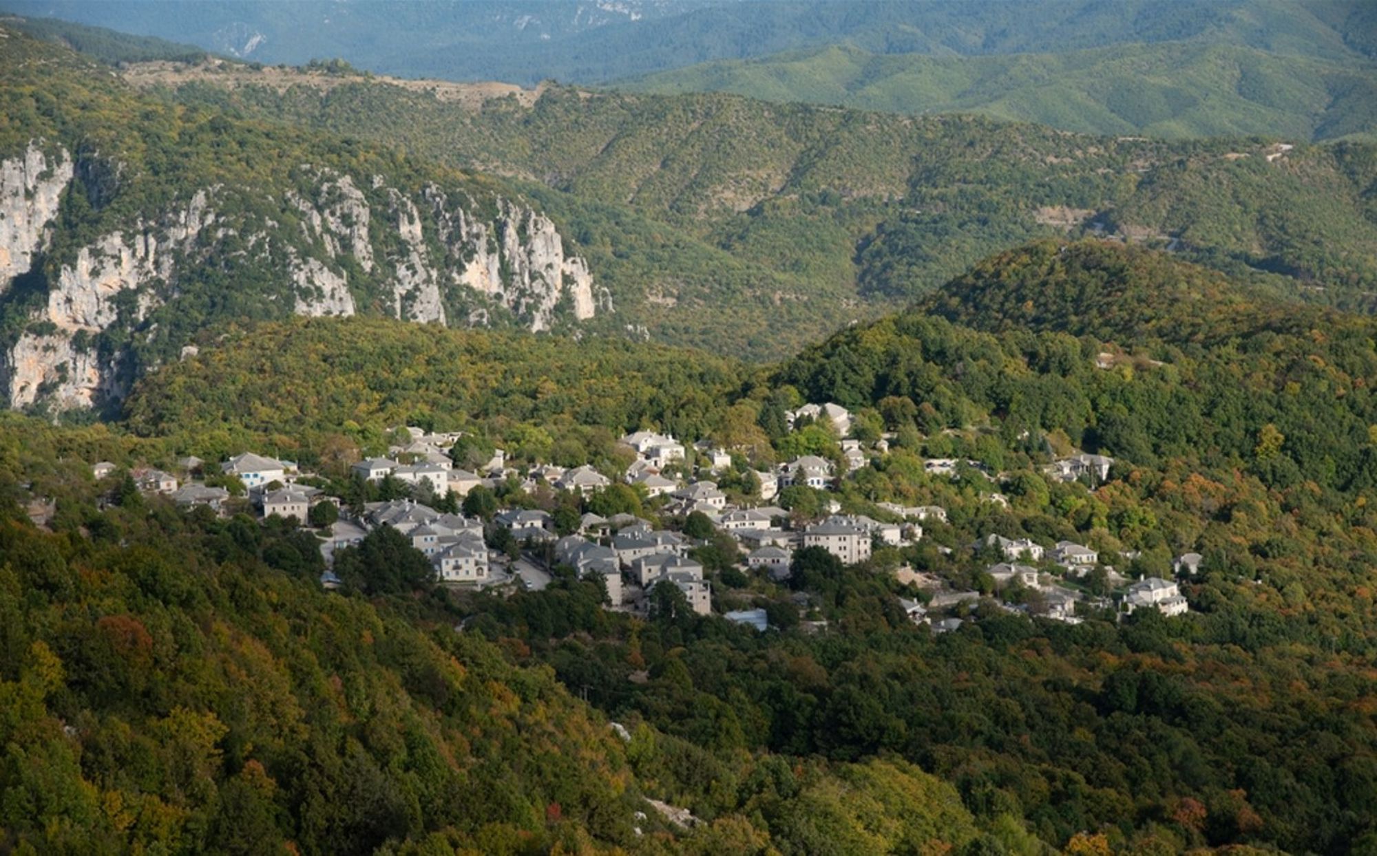 Bergdorp in de groene bergen van Griekenland, omringd door bossen en rotswanden.