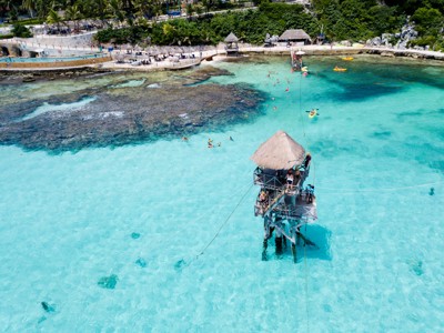 Uitzicht op turquoise zee bij Cozumel met snorkelaars en een houten uitkijktoren aan de kust van Mexico.