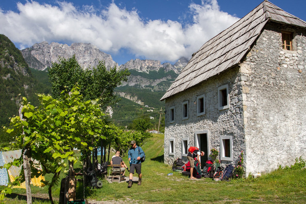Wandelaars bij een berghut tijdens de wandelvakantie Peaks of the Balkan, met uitzicht op ruige bergtoppen.