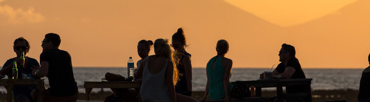 Jongeren genieten van de zonsondergang aan zee tijdens een Sawadee jongerenreis.
