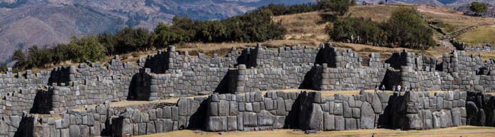 Massieve stenen muren van de Inca-ruïnes van Sacsayhuamán bij Cusco, Peru, met bergen op de achtergrond.