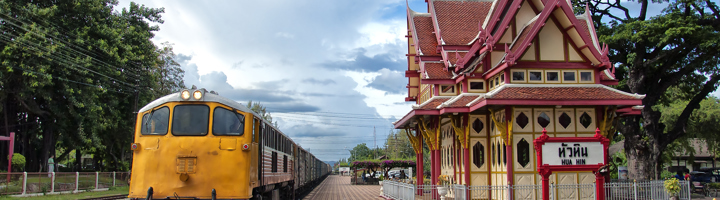 Trein bij het station van Hua Hin met het iconische Thaise stationsgebouw en het bord Hua Hin.