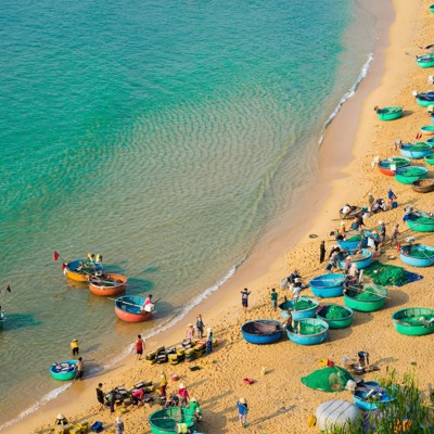Vissersboten en ronde mandboten op het strand in Vietnam tijdens Familiereis Vietnam Kort.