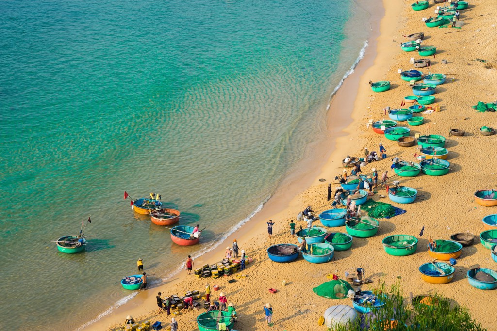 Vissersboten en ronde mandboten op het strand in Vietnam tijdens Familiereis Vietnam Kort.