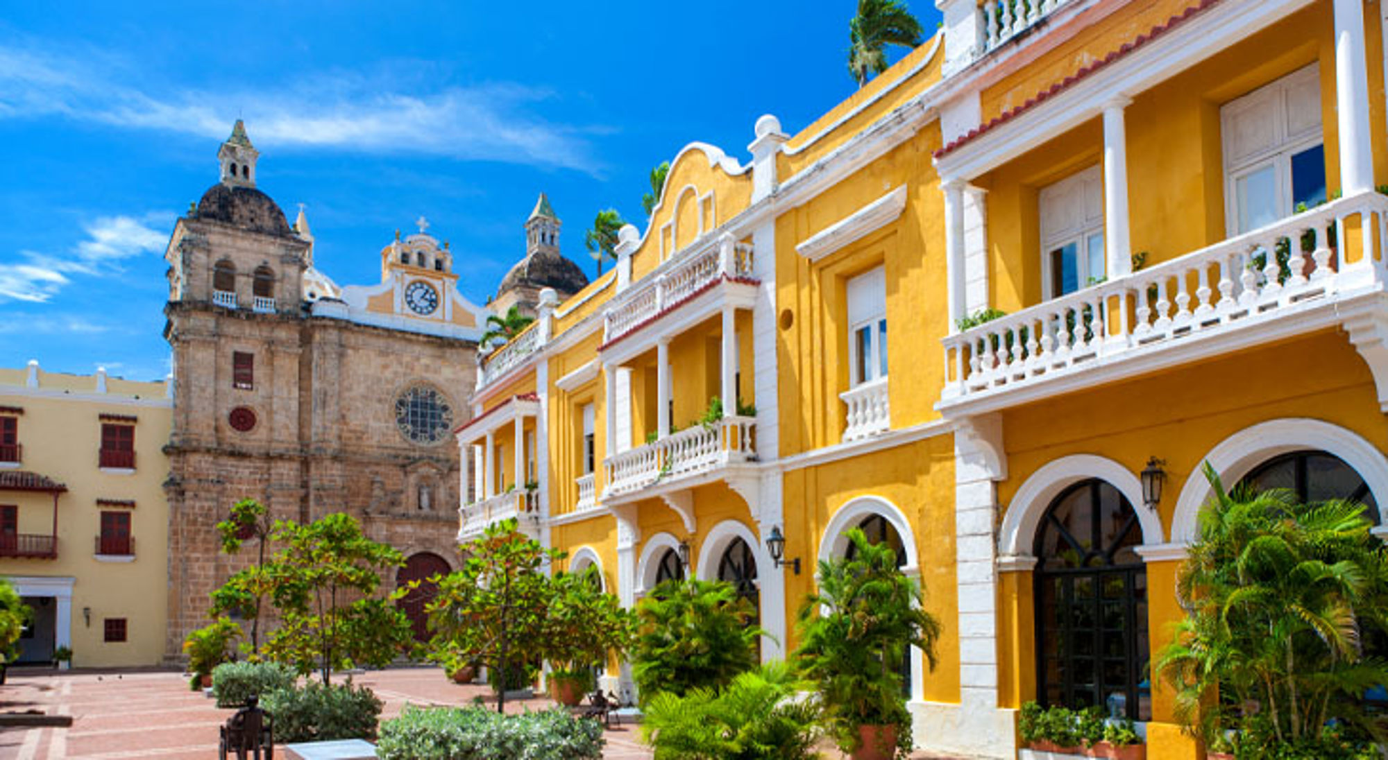 Gele gevels en de kathedraal aan Plaza de la Aduana in Cartagena, Colombia.