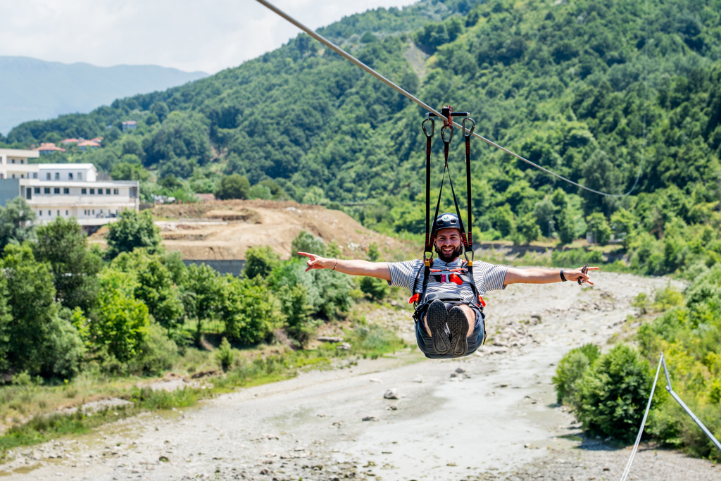 Man op zipline boven rivier in de bergen tijdens 22-35ers reis Albanië.